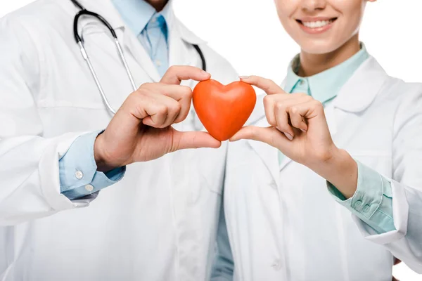 Imagen recortada de los médicos jóvenes con abrigos médicos que muestran el símbolo del corazón aislado en blanco - foto de stock