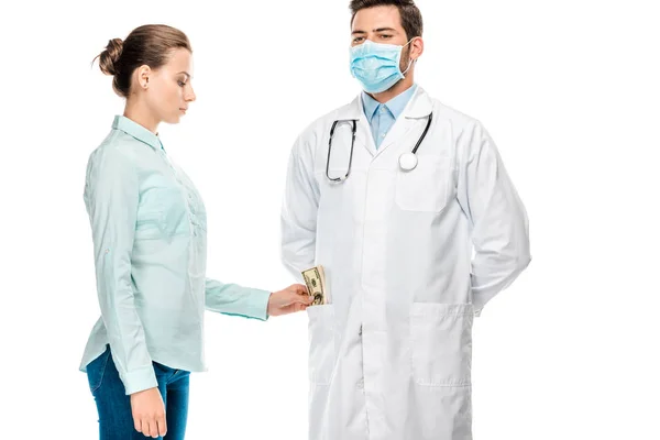 Vista lateral de paciente femenino poniendo soborno en bolsillo de joven médico masculino aislado en blanco - foto de stock