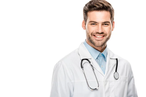 Médico macho feliz em casaco médico com estetoscópio sobre o pescoço olhando para a câmera isolada no branco — Fotografia de Stock