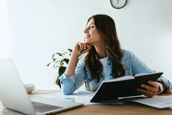 Donna d'affari pensierosa con notebook seduto sul posto di lavoro con documenti e laptop in ufficio — Foto stock