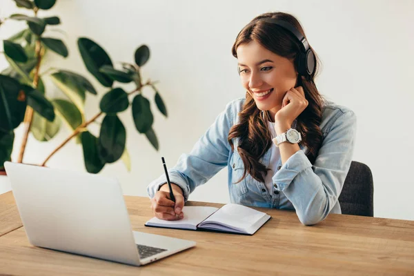 Portrait of young smiling woman in headphones taking part in webinar in office — Stock Photo