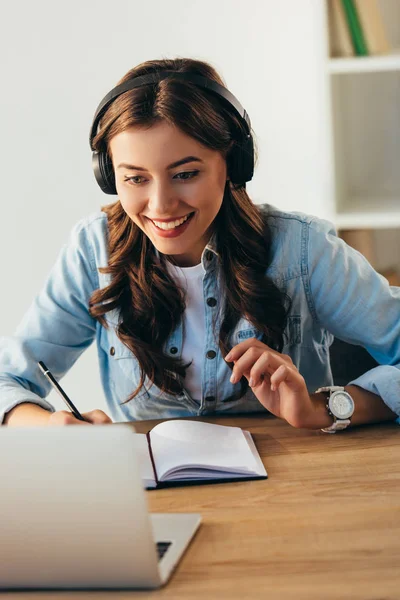 Portrait of young smiling woman in headphones taking part in webinar in office — Stock Photo