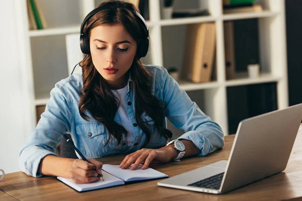 Junge Frau mit Kopfhörer nimmt an Webinar im Büro teil — Stockfoto