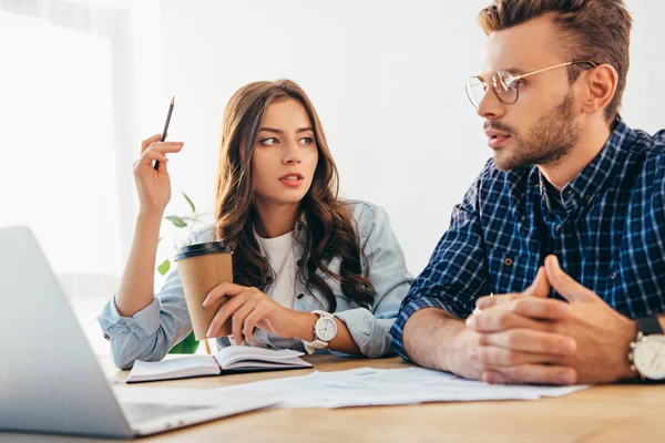 Berufskollegen nehmen an Webinar am Tisch mit Papieren und Laptop im Büro teil — Stockfoto