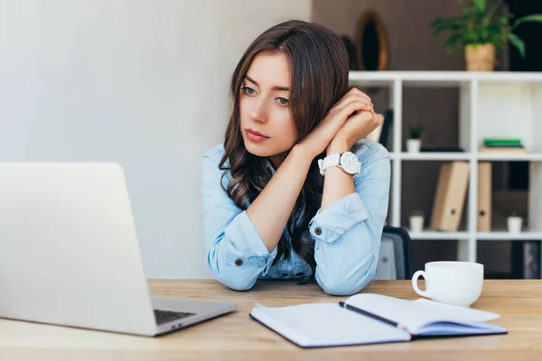 Junge Frau am Tisch mit Laptop nimmt an Webinar im Büro teil — Stockfoto