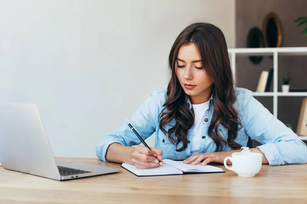 Молода жінка на столі з ноутбуком бере участь у вебінарі в офісі — Stock Photo