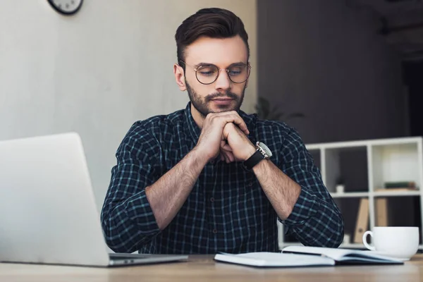 Портрет задумчивого бизнесмена в очках на рабочем месте с ноутбуком и ноутбуком — стоковое фото