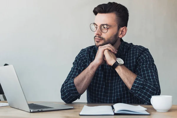 Retrato de empresário pensativo no local de trabalho com laptop e notebook — Fotografia de Stock