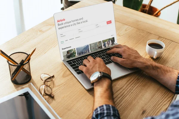 Partial view of businessman working on laptop with airbnb website at tabletop — Stock Photo