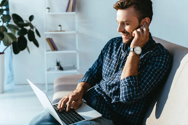 Vista lateral del hombre sonriente en auriculares que participan en webinar en casa - foto de stock