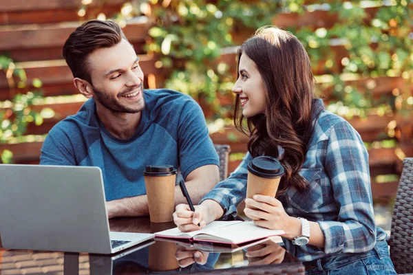 Jeunes amis à la table avec ordinateur portable et café pour aller participer à un webinaire ensemble dans un café — Photo de stock