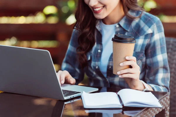 Partial view of smiling woman with coffee to go taking part in webinar — Stock Photo