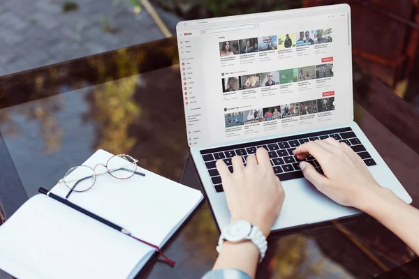 Cropped shot of businesswoman working on laptop with youtube website at tabletop with blank notebook — Stock Photo