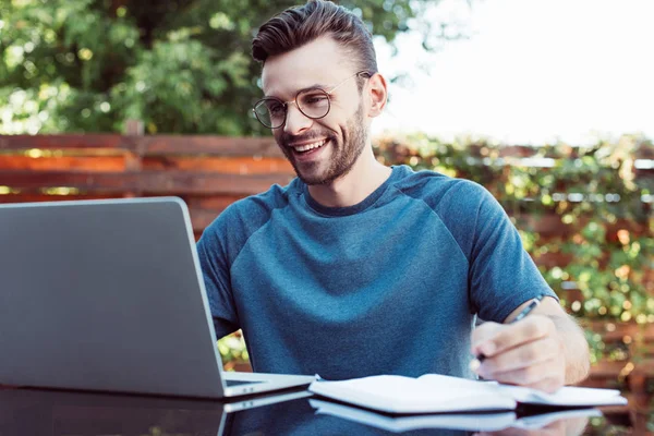 Sorrindo bonito homem participando de webinar ao ar livre — Fotografia de Stock