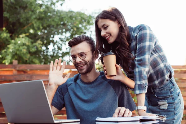 Smiling colleagues taking part in webinar and waving hand — Stock Photo