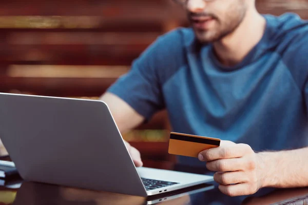 Abgeschnittenes Bild eines Mannes, der online mit Kreditkarte und Laptop am Tisch einkauft — Stockfoto