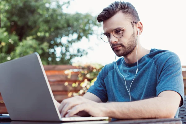 Handsome man taking part in webinar at table in park — Stock Photo