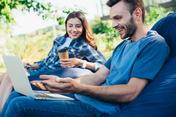 Colegas emocionados que participan en webinar sobre sillas de bolsa de frijoles en el parque - foto de stock