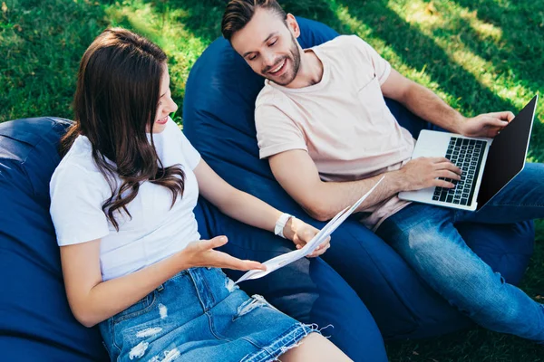 Vista ad alto angolo dei colleghi che partecipano al webinar sulle sedie del sacchetto di fagioli nel parco — Foto stock