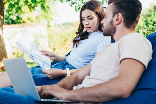 Colegas que participam de webinar sobre cadeiras de saco de feijão no parque e olhando para documentos — Fotografia de Stock