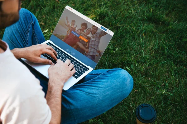 Обрезанное изображение человека с помощью ноутбука с веб-сайтом каучсерфинга в парке — стоковое фото