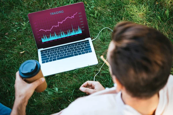 High angle view of man using laptop with trading appliance in park — Stock Photo