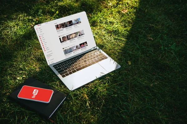 Gadgets com páginas carregadas do youtube na grama verde no parque — Fotografia de Stock