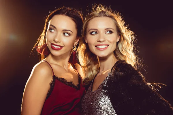 Portrait of smiling attractive women in glamour dresses on black with backlit — Stock Photo