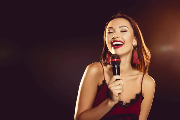 Retrato de mujer seductora con micrófono en mano cantando karaoke - foto de stock