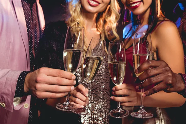Vista recortada de amigos glamorosos tintineo con copas de champán - foto de stock
