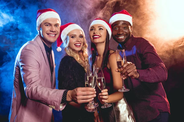 Luxury multiethnic people in santa hats clinking with champagne glasses on new year party — Stock Photo