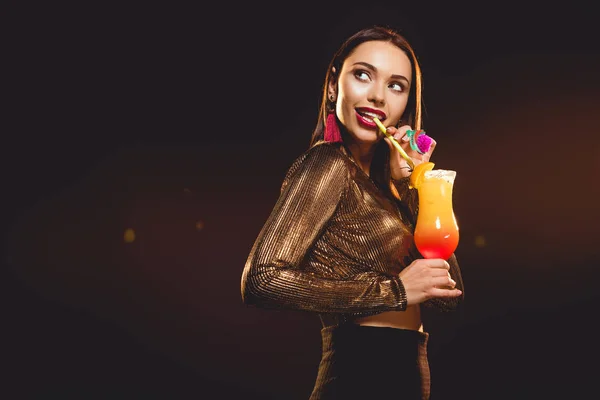 Brunette glamorous young woman drinking alcohol cocktail on black — Stock Photo