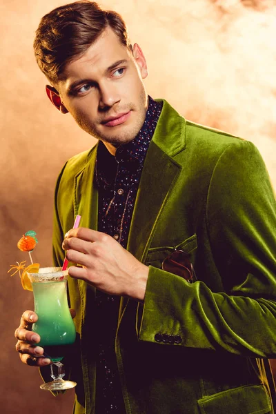 Handsome man in green jacket holding alcohol cocktail on party with smoke — Stock Photo