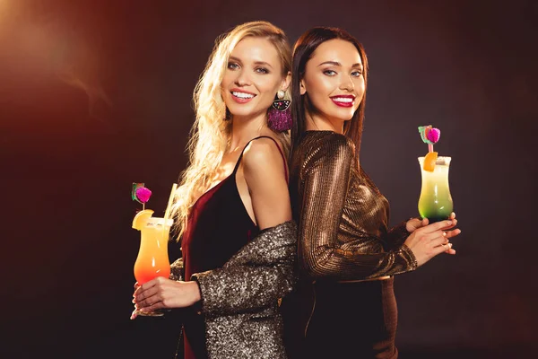 Красивые улыбающиеся женщины позируют со сладкими алкогольными коктейлями — стоковое фото