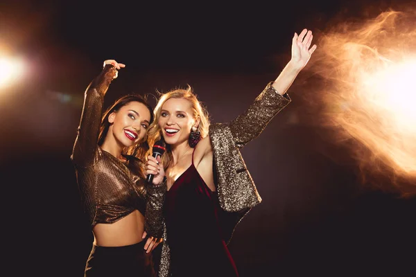 Hermosas chicas felices bailando y cantando con micrófono en karaoke - foto de stock
