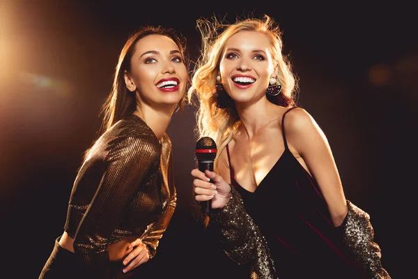 Attractive cheerful women singing with microphone in karaoke — Stock Photo