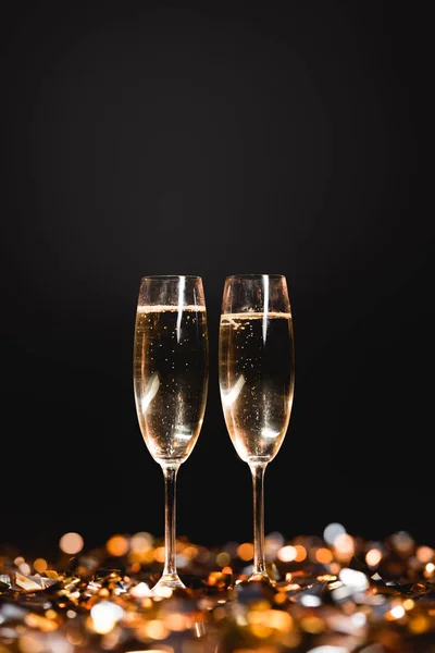 New year celebration with champagne glasses on golden confetti on black — Stock Photo