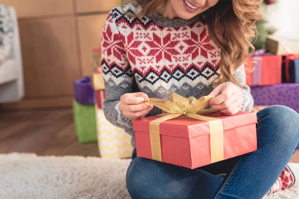 Image recadrée de femme souriante préparant un cadeau pour la veille de Noël à la maison — Photo de stock