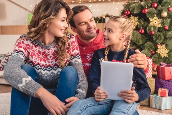 Parents et fille utilisant la tablette ensemble près de l'arbre de Noël à la maison, se regardant — Photo de stock