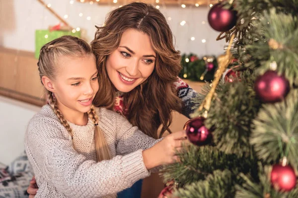 Glückliche Mutter und Tochter schmücken Weihnachtsbaum zu Hause mit Christbaumkugeln — Stockfoto