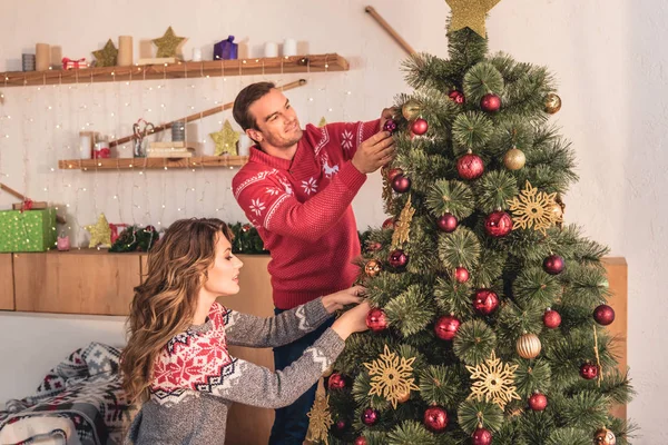 Beautiful couple decorating christmas tree together — Stock Photo