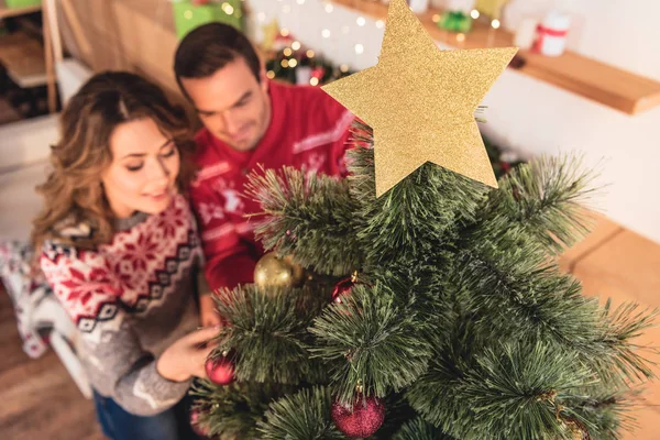 Enfoque selectivo de la estrella de Navidad de oro y pareja decorando el árbol de Navidad - foto de stock