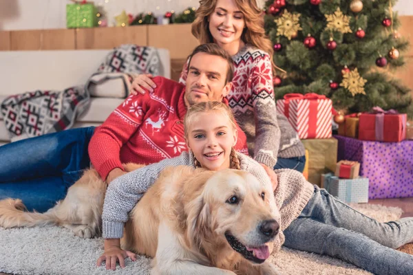 Familia feliz con perro golden retriever acostado cerca del árbol de Navidad en casa — Stock Photo