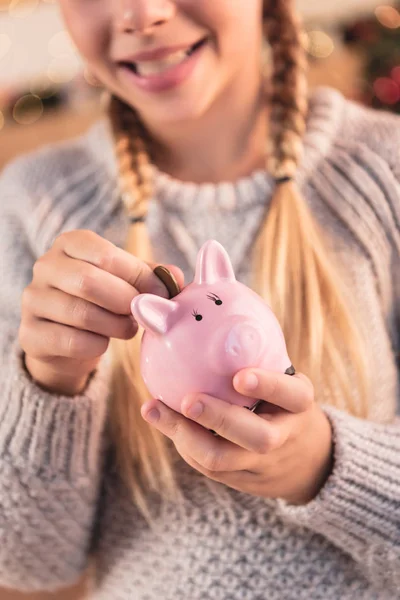 Cropped view of kid putting coin into piggy bank — Stock Photo