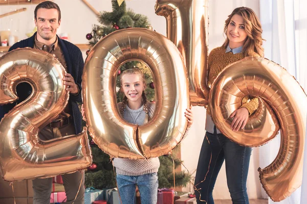 Счастливая семья с дочерью, держащей золотые воздушные шары 2019 года — стоковое фото