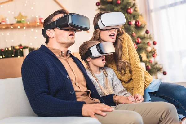 Familia conmocionada usando auriculares de realidad virtual en casa en Navidad - foto de stock