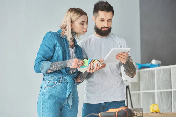 Paar hält Farbpalette und verwendet digitales Tablet während der Reparatur — Stockfoto