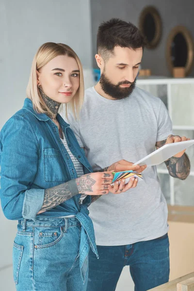 Giovane coppia tatuata utilizzando tablet digitale insieme in una nuova casa — Foto stock