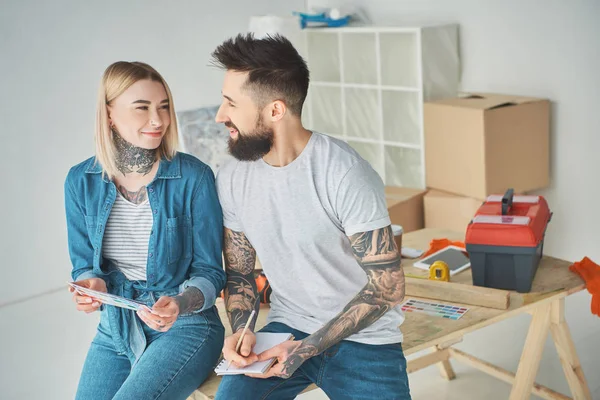 Feliz jovem casal segurando paleta de cores e notebook na nova casa — Fotografia de Stock