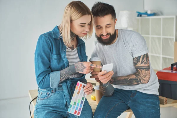 Happy young couple using smartphone during house repair — Stock Photo